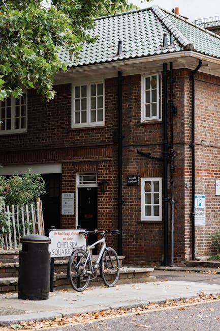 The image shows the exterior of a traditional brick terraced house on Kings Road in Chelsea, featuring a grey tiled pitched roof with chimney stacks and black guttering along the roofline. A small, we